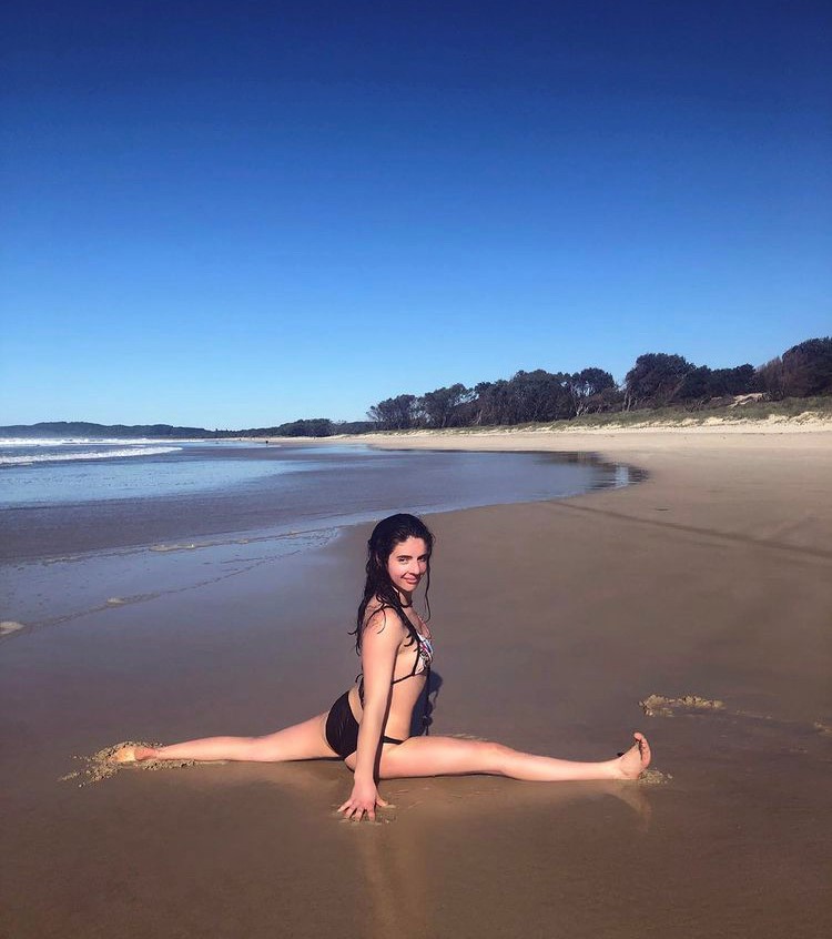 girl doing splits on beach